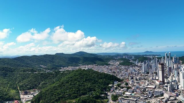 Balne&aacute;rio Cambori&uacute;: A vibrant city with a stunning skyline and lush green hills.