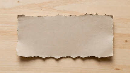 Torn paper on a wooden surface viewed from directly above showing rough texture and edges