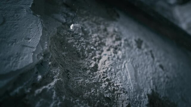 Rough wall texture revealed in blue backlight within underground room. low light background suited for crime, mystery, or horror settings.