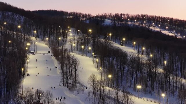 Aerial drone view of illuminated Bromont ski resort slopes at dusk, Quebec, Canada in winter. g.