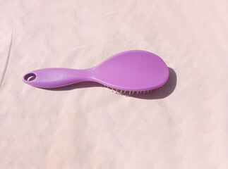 Purple hairbrush on light background for hair care