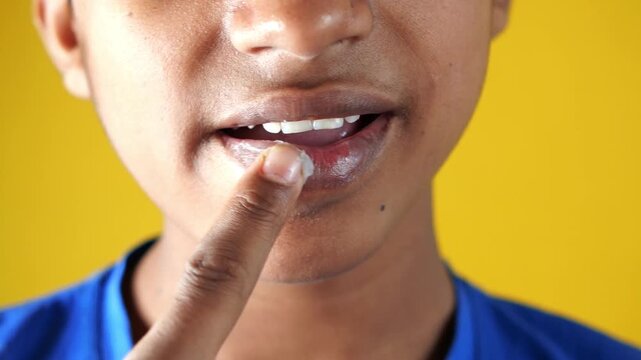 Close-up cinematic footage of young person applying lip balm on chapped lips, showcasing daily skincare and lip care routine in dynamic motion