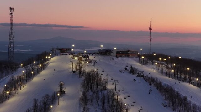 Aerial drone view of illuminated Bromont ski resort slopes at dusk, Quebec, Canada in winter. g.