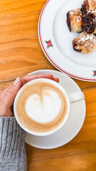 Fototapeta premium Cup of Coffee with Pastry on Wooden Table, Cozy Café Breakfast