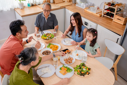 Asian loving family spending quality time, having dinner in cozy house. 
