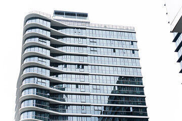 Modern curved glass high-rise building with reflective windows in urban skyline
