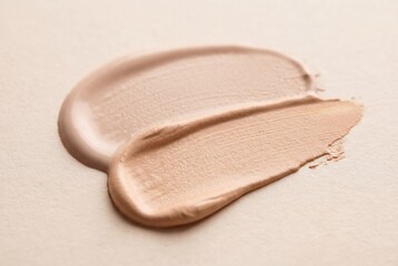 Fototapeta premium Two cosmetic foundation swatches with different tones and textures on a light beige surface