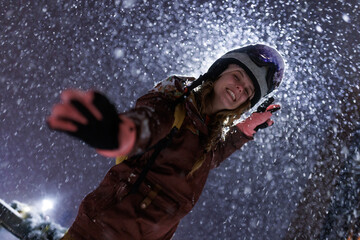 Snowboarder enjoys night ride in snowstorm at mountain resort during winter season with snowflakes falling around