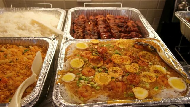 Filipino food spread featuring various dishes and desserts at a gathering in a home kitchen