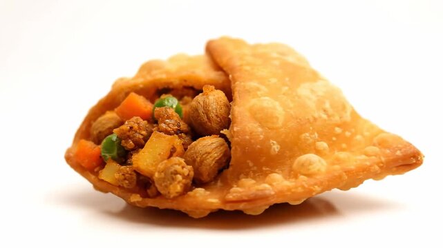 Golden fried savory pastry (samosa or karipap) cut in half, revealing a rich filling of minced meat, peas, and carrots, isolated on a white background.