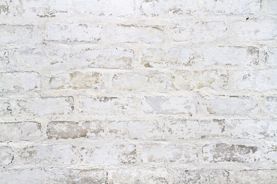 An old peeling white brick wall. Texture of whitewashed brickwork