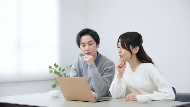 部屋でノートパソコンを見る男女カップル