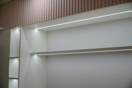 White wall with a shelf and a light fixture above it