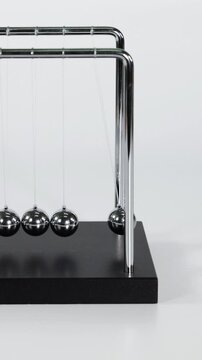 Vertical Close Up of Hand Starting Motion on Newton's Cradle
