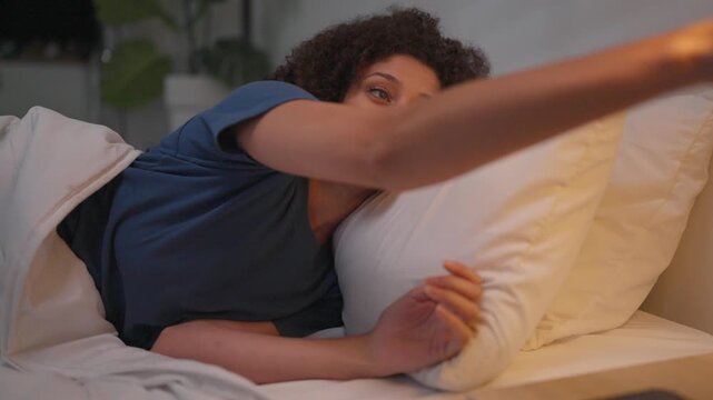Attractive Latina woman lying on bed in a dark bedroom at night.