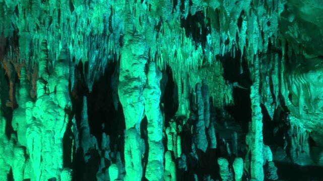 Pan left shot of illuminated stalactites and stalagmites in cave. Florida Caverns State Park