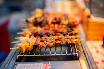 An Asian woman is strolling through a night market, enjoying traditional street food, colorful lanterns, and smiling at the bustling city stalls. It's a vibrant atmosphere and a wonderful cultural 