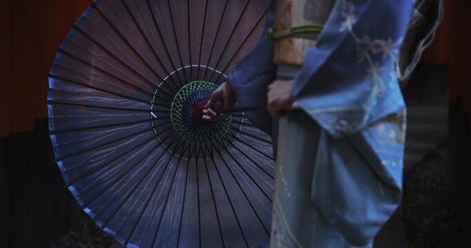 Closeup on woman in kimono closing her beautiful, old umbrella