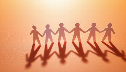 Paper cutouts of people holding hands create sense of unity and connection, casting shadows on warm orange background