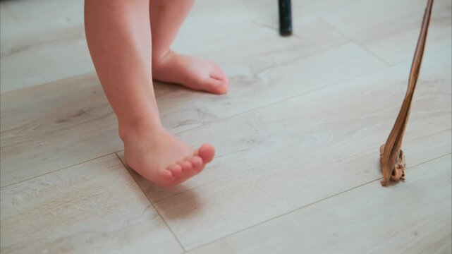 A Close-Up View of a Child's Feet Standing on a Light-Colored Wooden Floor, Highlighting the Innocence of Early Steps and Playful Moments