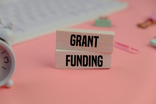 Business financing and grants concept. Copy space. GRANT FUNDING on a white blocks on the pink color background 