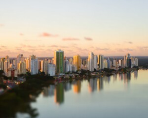 Obraz premium Aerial city skyline reflecting in lake water during sunset with soft pastel tones for urban development presentations and commercial real estate background