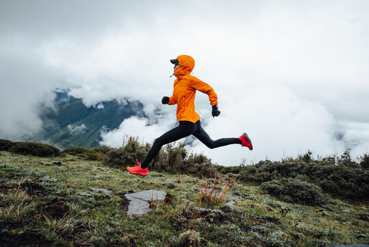 Woman trail runner cross country running at high altitude mountain peak