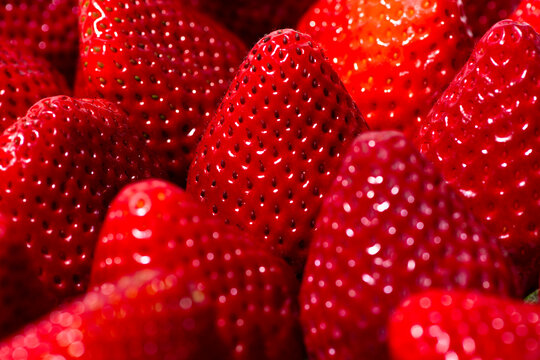 Strawberries macro texture. Red strawberries with glossy fruit. Strawberries close up for background. Fresh strawberries with berry pattern.