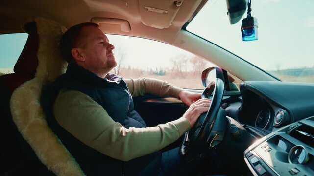 A contemplative moment inside a car as the driver gazes out at the scenic landscape, reflecting on thoughts while enjoying the comfort of a plush seat cover during a leisurely drive.
