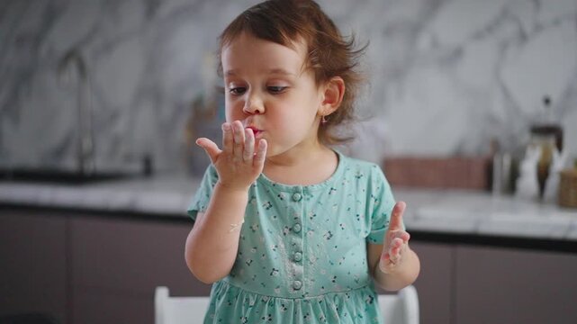 Young Child Engaged in Playful Activity in a Modern Kitchen, Exploring Textures and Sensations with a Curious Expression and Playful Gestures