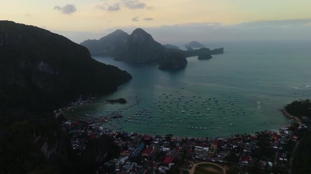 Cinematic drone view of El Nido bay in Palawan, Philippines. High-angle shot of hundreds of outrigger boats docked near the town, surrounded by iconic limestone cliffs at sunset