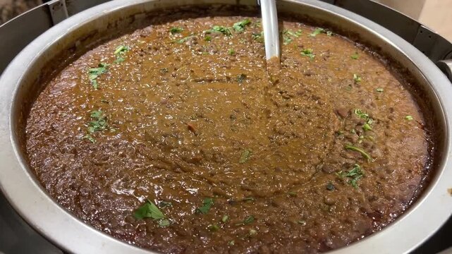 A vibrant, steaming bowl of authentic Indian Dal Tadka Fry tempered with ghee and aromatic spices, elegantly served in a traditional copper handi at a festive wedding banquet.