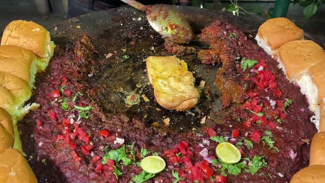 A vibrant street-style Kutch Dabeli featuring a spicy potato filling tucked into a toasted bun, topped with crunchy peanuts, pomegranate seeds, and fresh sev, served against a colourful Indian festiva