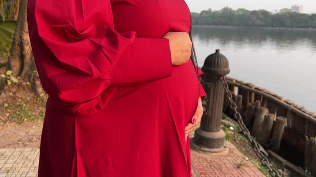 An Indian woman posing for a maternity shoot near a lake in India