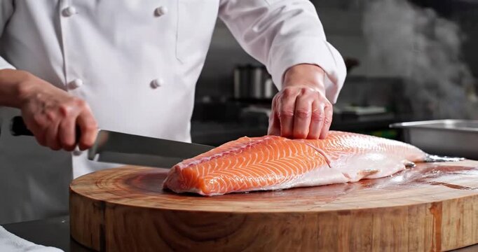Chef skillfully filleting fresh salmon on a wooden cutting board in a modern kitchen