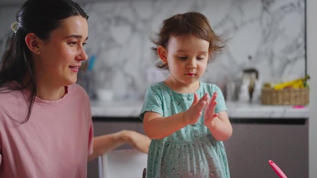 A Heartwarming Moment of Connection: A Mother and Her Young Daughter Engaging in Playful Interaction in a Bright and Modern Kitchen Setting