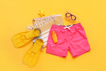 Swimming trunks with beach accessories on yellow background © Pixel-Shot