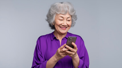 Fototapeta premium Elderly woman in a purple blouse smiles as she engages with her smartphone, creating joyful moments Generative AI