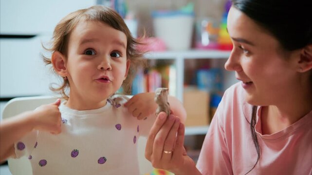 A Heartwarming Moment: A Young Girl Joyfully Engages with Her Mother while Admiring a Small Animal in a Playful and Nurturing Environment