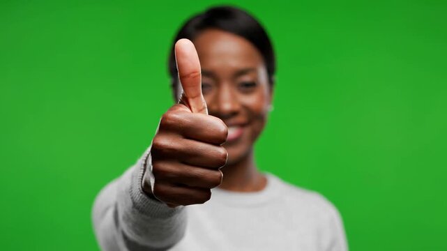 A young woman giving a thumbs up gesture with a green background