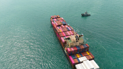 Fototapeta premium Aerial top view over international containers cargo ship at industrial import-export port prepare to load containers with big container loader ship vessel. global transportation and logistic business.