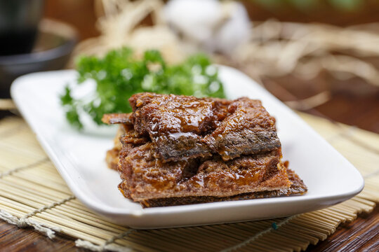 Flavored braised ribbonfish served on a rounded, elongated porcelain plate