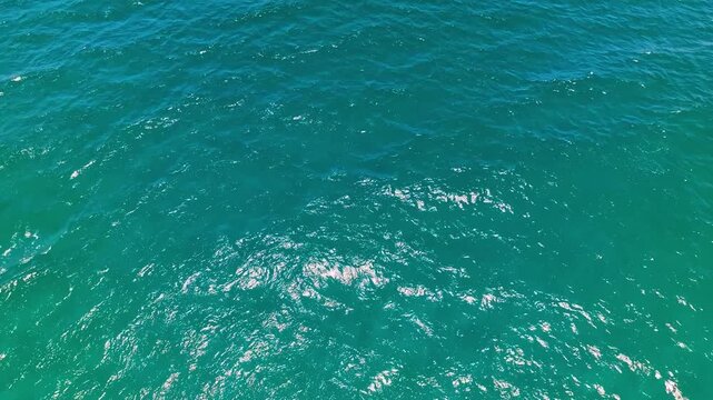 Crystal clear seawater texture, drone view. Reflection of turquoise water in a tropical ocean. Bird's eye view of the sea. Blue waves and water surface texture. Natural background of summer sea waves.