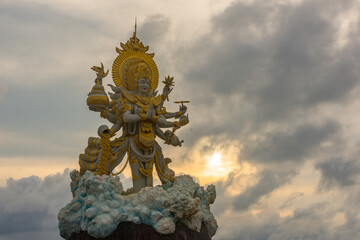 Majestic Multi-Armed Hindu Deity Statue Under Dramatic Clouds &ndash; Bali Spiritual Power