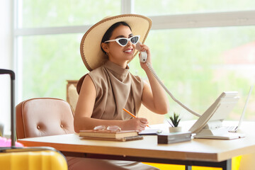 Young businesswoman talking by telephone before vacation in office