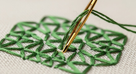 A close-up macro view of a gold needle performing intricate green embroidery stitches on a light fabric