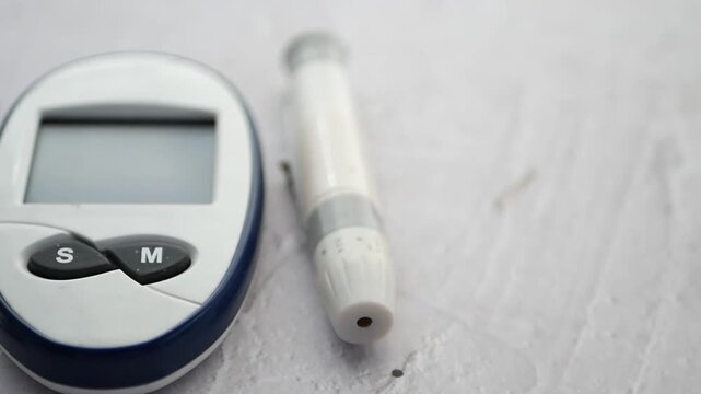 A close up cinematic motion footage of a glucometer with lancet and blister pack pills slowly rotating, highlighting diabetes management equipment and medical supplies