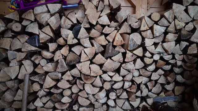 Camera panning across a large stack of firewood in a shed