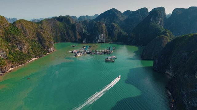 Aerial view of Halong bay with speedboats and tourist yacht conduct tour between limestone islets sunset time, tourist landmark of Vietnam.