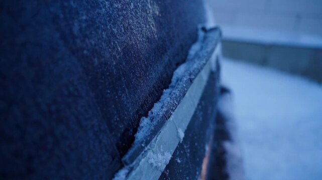 Car rear window wiper covered in ice, close-up.